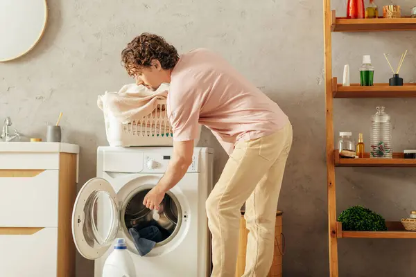 Um homem de roupa de casa aconchegante fazendo algo dentro de uma máquina de lavar roupa. — Fotografia de Stock