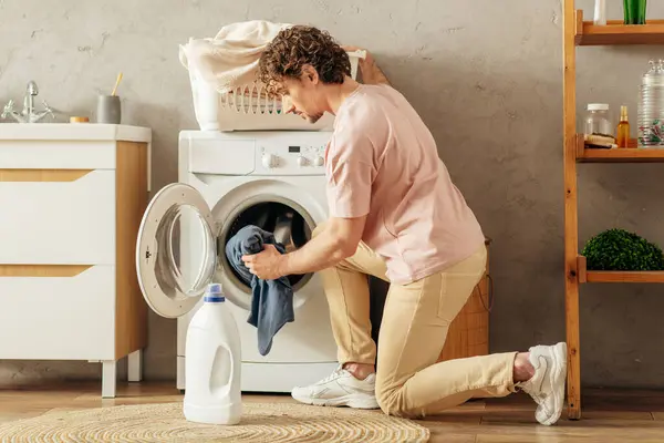 Hombre carga alegremente la ropa en la lavadora. - foto de stock