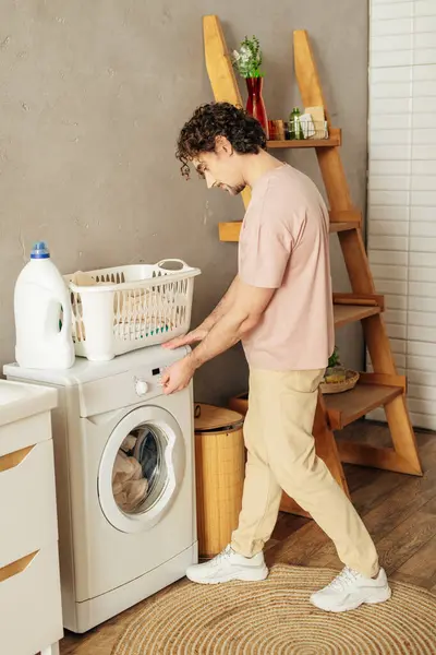 Ein Mann in kuscheliger Hauskleidung lädt eine Waschmaschine. — Stockfoto