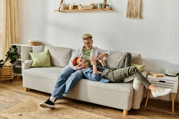 Two women, a lesbian couple with short hair, are sitting comfortably on a couch in a cozy living room. — Stock Photo