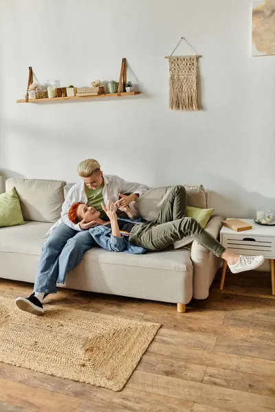 Two women with short hair sitting closely on a couch in a cozy living room, sharing a moment of connection and intimacy. — Stock Photo