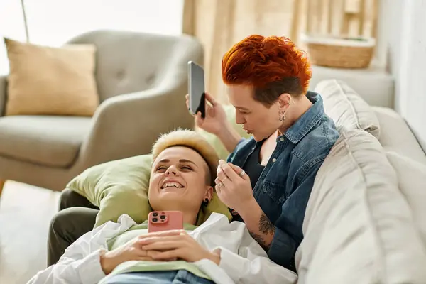Two women with short hair sit on a couch, engrossed in conversation, showcasing love and connection. — Stock Photo