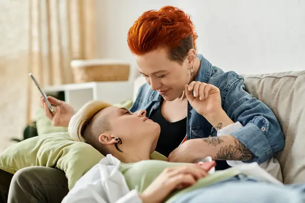 Dos mujeres lgbt con el pelo corto se sientan de cerca en un sofá, participan en una conversación profunda. - foto de stock