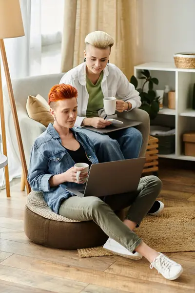 Um casal lésbico com cabelo curto relaxa em um saco de feijão em uma sala de estar acolhedora, desfrutando de um momento calmo e calmante juntos.. — Fotografia de Stock