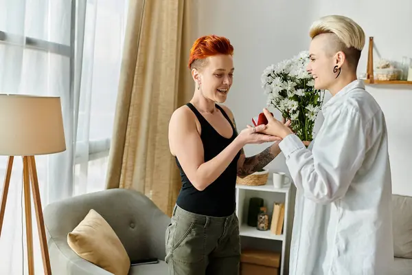 Two women with short hair happily exchanging gifts in a cozy living room setting. — Stock Photo