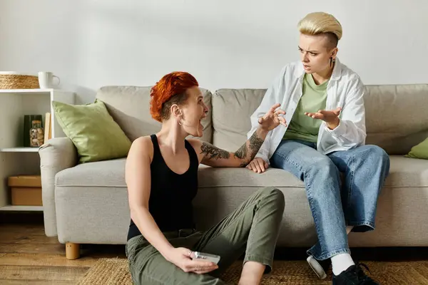 Zwei Frauen mit kurzen Haaren sitzen auf einer Couch und unterhalten sich emotional — Stockfoto
