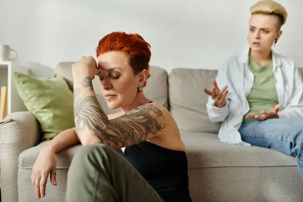 Two women, a lesbian couple with short hair, sit on a couch, engrossed in conversation — Stock Photo