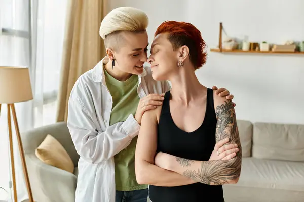 Two women, a lesbian couple with short hair, tenderly hug each other in their cozy living room, showcasing love and unity. — Stock Photo