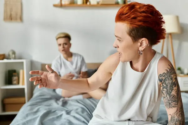 Couple lesbien aux cheveux courts assis sur un lit, engagé dans la conversation, argumentant — Photo de stock