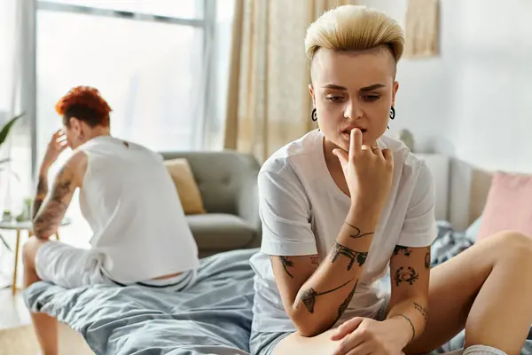 Offensé couple lesbien avec tatouages assis sur un lit dans une chambre — Photo de stock