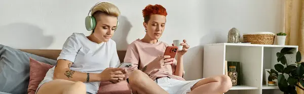 Deux jeunes hommes assis sur un lit, absorbés par les jeux de smartphone ensemble. — Photo de stock