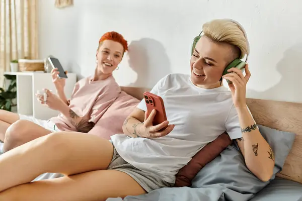 Coppia lesbica con i capelli corti trascorrere del tempo di qualità giocando insieme su un letto accogliente nella loro camera da letto. — Foto stock