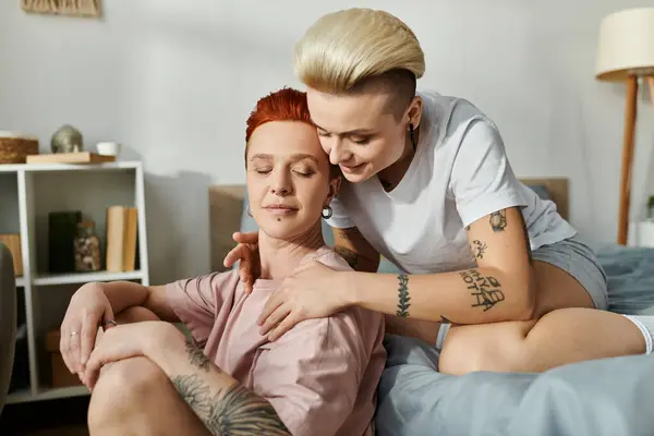 Ein lesbisches Paar mit kurzen Haaren, das sich warm umarmt, während es auf einem Bett liegt und Liebe und Nähe zeigt. — Stockfoto