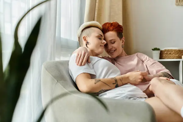 Um momento sincero entre um casal lésbico, sentado em um sofá, abraçando um ao outro com amor em um quarto acolhedor. — Fotografia de Stock