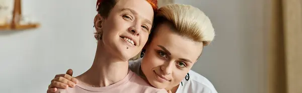 Dos mujeres con pelo corto se abrazan en un cálido abrazo, mostrando amor y conexión en su dormitorio compartido. - foto de stock