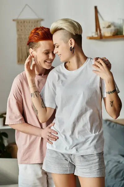 Zwei Frauen mit kurzen Haaren umarmen sich in einem warmen Wohnzimmer und zeigen Liebe und Unterstützung im LGBT-Lebensstil. — Stockfoto