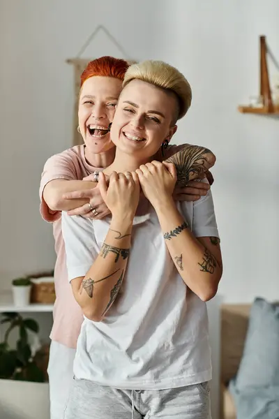 Two women with short hair sharing a heartfelt embrace in a cozy living room, expressing love and connection. — Stock Photo