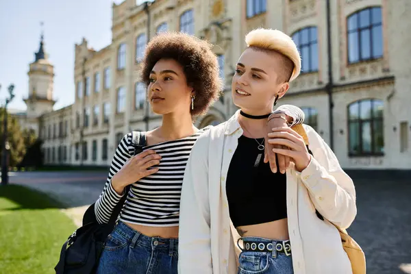 Two young women stand confidently in front of a modern building on a university campus. — Stock Photo
