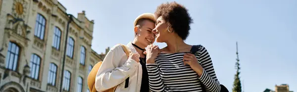 Two young women, a multicultural lesbian couple, express love with a kiss on the street near a university campus. — Stock Photo