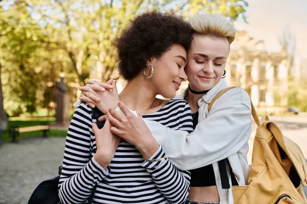 Giovane coppia lesbica multiculturale che condivide un abbraccio sincero in un bellissimo parco. — Foto stock