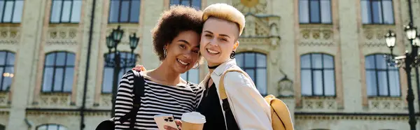Two young women, stylishly dressed, posing confidently in front of a striking building. — Stock Photo