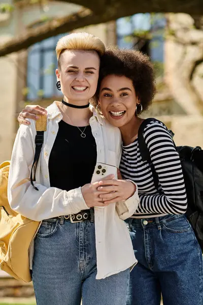 Two young women standing in front of a campus, posing for a photo together with genuine smiles. — Stock Photo
