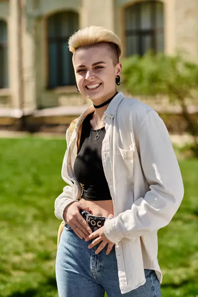 A stylish young woman in jeans and a white shirt striking a pose in front of a building on a university campus. — Stock Photo