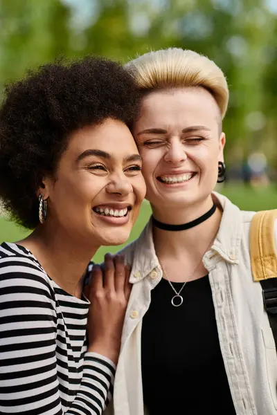 Two young women exuberantly laugh together while enjoying time in a park near a university. — Stock Photo