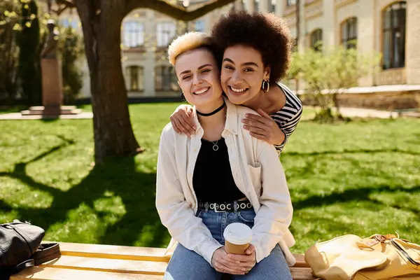 Deux jeunes filles en tenue décontractée, profitant d'un moment paisible ensemble sur un banc dans un cadre de parc serein. — Photo de stock