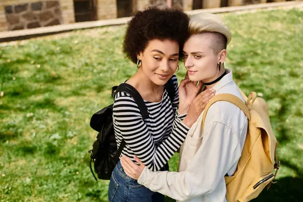 Zwei junge Frauen in legerer Kleidung umarmen sich liebevoll auf dem Rasen und teilen einen Moment echter Verbundenheit. — Stockfoto