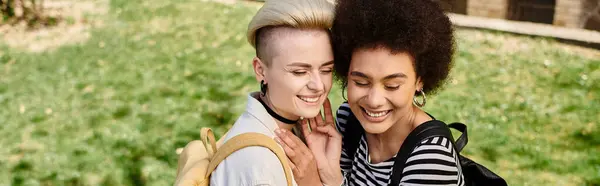 Dos chicas jóvenes con atuendo casual compartiendo un cálido abrazo en medio de la exuberante hierba verde. — Stock Photo