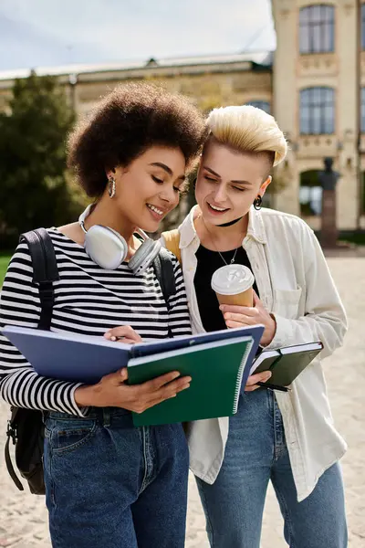 Две молодые женщины погрузились в книгу, наслаждаясь вместе кофе.. — Stock Photo