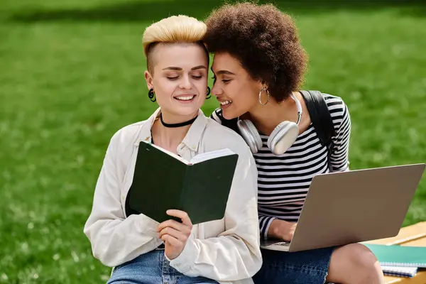 Zwei junge Frauen sitzen auf einer Bank, in ein Buch vertieft, und genießen einen friedlichen Moment des gemeinsamen Lesens und der Geselligkeit. — Stockfoto