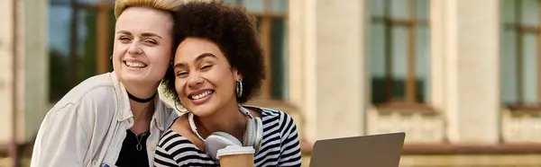 Two women working together on a laptop while sitting on a bench. — Stock Photo