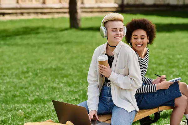 Zwei junge Frauen sitzen auf einer Bank im Park, unterhalten sich und genießen die friedliche Umgebung der Natur. — Stockfoto