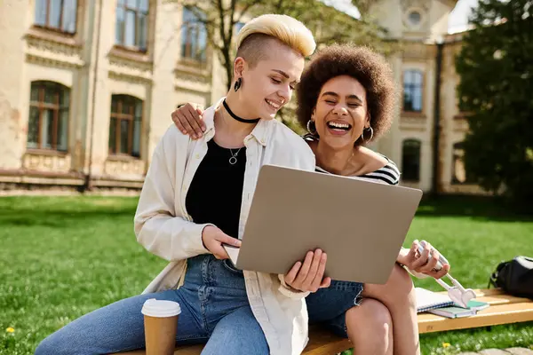 Two women immersed in their work, sitting on a bench outdoors, focused on the laptop screen in front of them. — Stock Photo