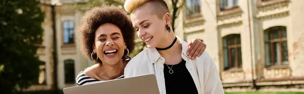 Two women joyfully smiling as they collaborate on a laptop together. — Stock Photo
