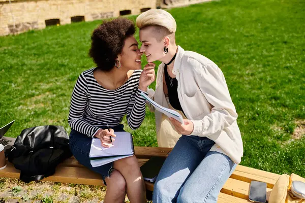 Zwei junge Frauen sitzen auf einer Bank und unterhalten sich lebhaft in einem Park. — Stockfoto