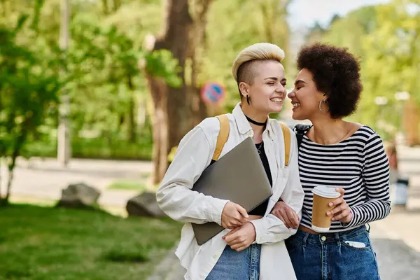 Two young women in casual attire chat in a park setting, connecting with one another in a peaceful outdoor environment near a university campus. — Stock Photo