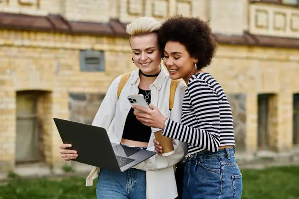 Due giovani donne in abiti eleganti, assorbiti nei loro computer portatili, concentrati sui loro schermi. — Foto stock