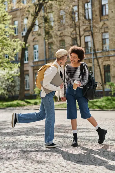 Stylish, casual, multicultural lesbian couple stroll on city street near university campus. — Stock Photo