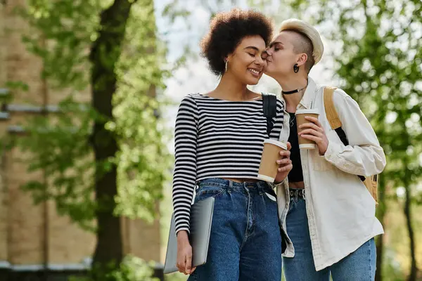A tender moment as two young women, a multicultural lesbian couple, share a kiss in the park, expressing their love openly. — Stock Photo