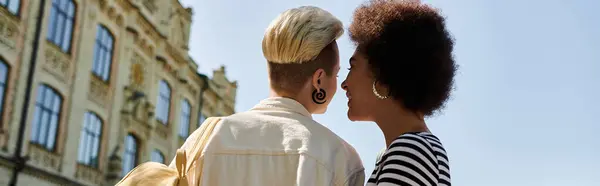 Two stylish black women share a tender kiss in front of a university building, showcasing love and diversity. — Stock Photo