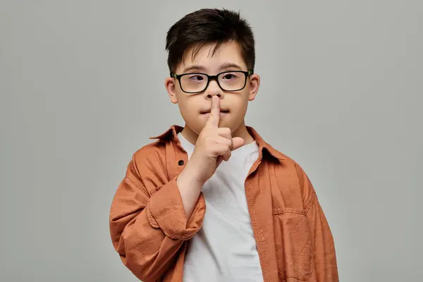 Мальчик с синдромом Дауна в очках делает знак молчания. — стоковое фото