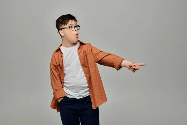 Niño pequeño con síndrome de Down con gafas apuntando con entusiasmo - foto de stock