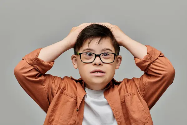 A little boy with Down syndrome with glasses is holding his head up in contemplation. — Stock Photo