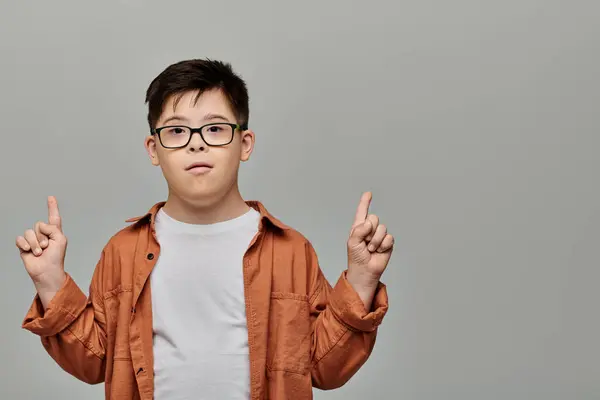 A little boy with Down syndrome with glasses playfully gesturing with his finger. — Stock Photo