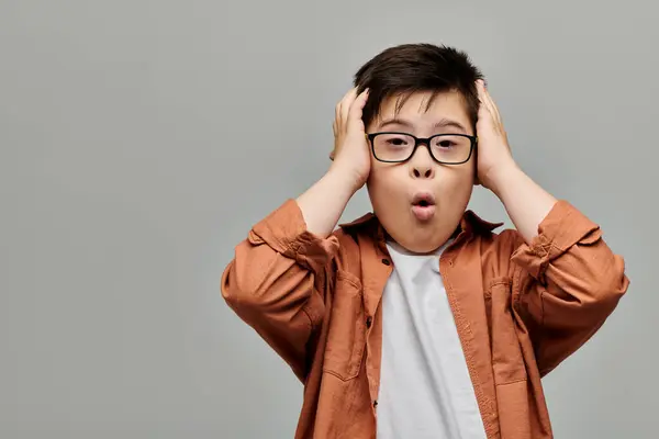 Boy with Down syndrome with glasses, with hands on head. — Stock Photo