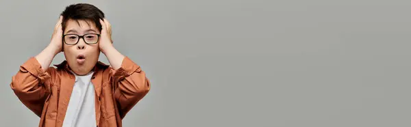 Little boy with Down syndrome with glasses, with hands on head. — Stock Photo