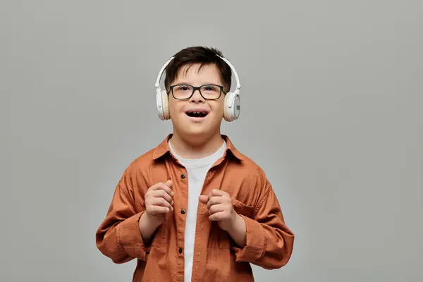 Ein fröhlicher kleiner Junge mit Down-Syndrom trägt Kopfhörer und strahlt mit einem Lächeln. — Stockfoto